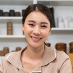 Portrait of Asian woman sell vase product online and looking at camera. Attractive young businesswoman using laptop computer checking sale order and feel happy with financial of business in warehouse.